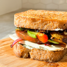 Toasted thick slices of Classic Bread SRSLY loaf made into a sandwich with mozzerella, tomato, red onion, chicken, and avocado