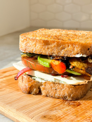 Toasted thick slices of Classic Bread SRSLY loaf made into a sandwich with mozzerella, tomato, red onion, chicken, and avocado