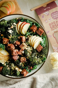 Bread SRSLY gluten-free Cinnamon Raisin sourdough bread cut into cubes and toasted to make croutons, atop a kale salad with sliced apples, roasted broccoli, and chopped nuts