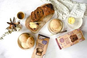 Bread SRSLY Gluten-Free Sourdough Sandwich Rolls and Cinnamon Raisin Sourdough Bread packaging, sliced loaf, and roll on table  with butter and coffee