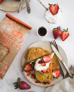Bread SRSLY Seeded gluten-free sourdough French Toast slices topped with whipped cream, maple syrup and sliced strawberries